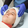 Woman receiving facial treatment with towel.